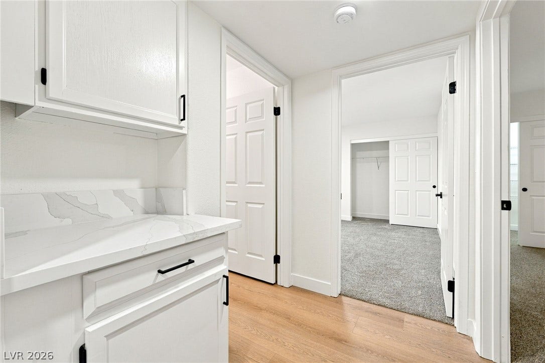 4500 W Lake Mead Boulevard, #102, Las Vegas, NV 89108 Crisp white cabinetry and stone countertops transition seamlessly into comfortable, carpeted bedrooms.