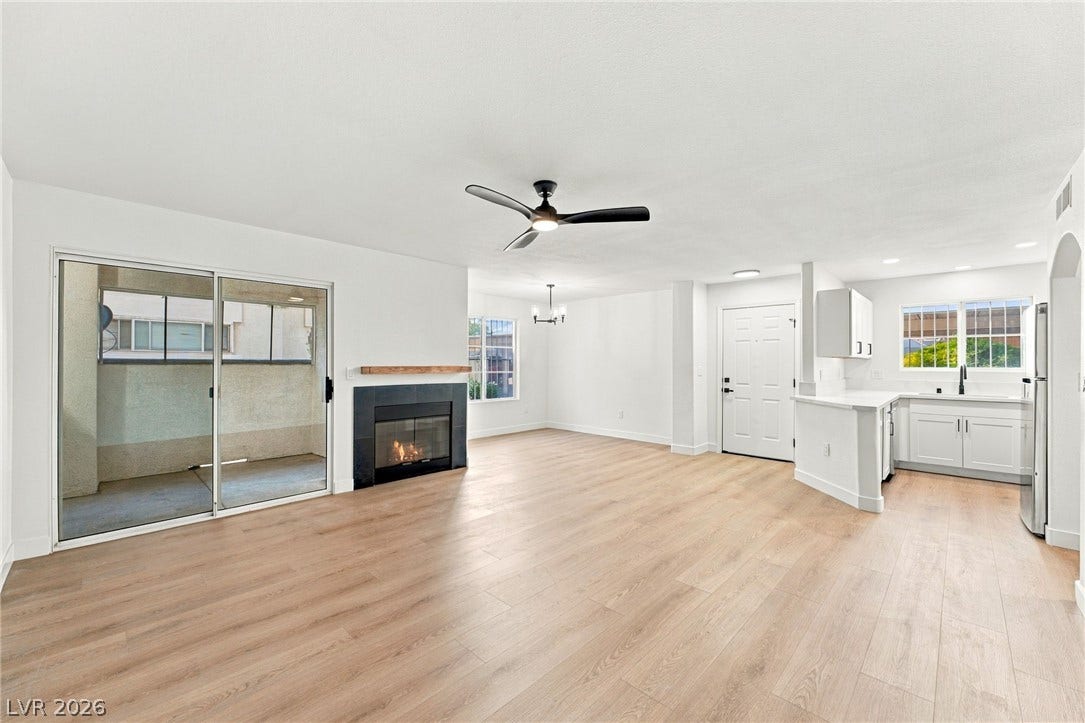 4500 W Lake Mead Boulevard, #102, Las Vegas, NV 89108 An open floorplan seamlessly connects the living space, fireplace, and kitchen over modern wood flooring.