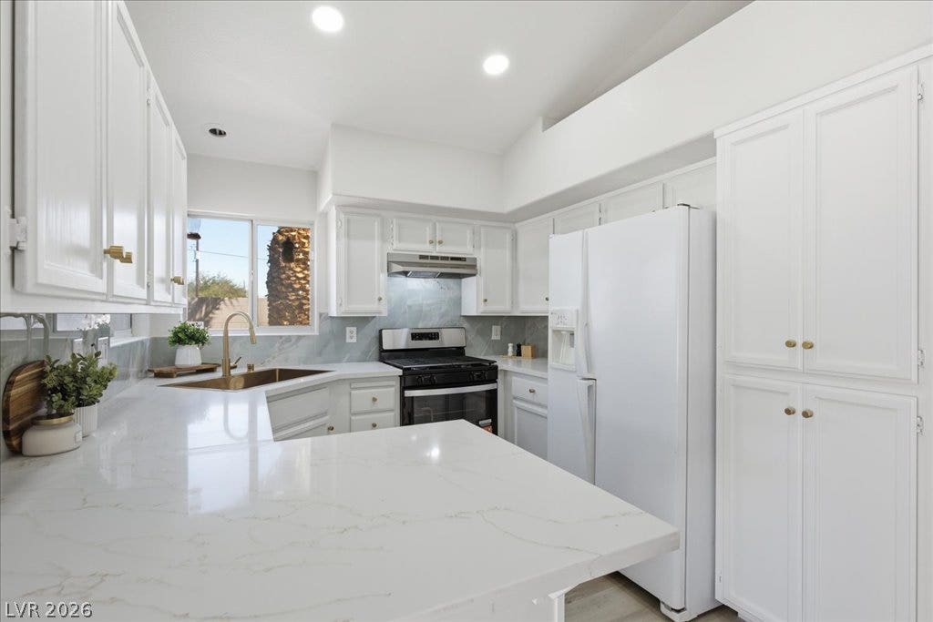 Bright recessed lighting illuminates the sleek stone countertops and classic cabinetry of this kitchen.