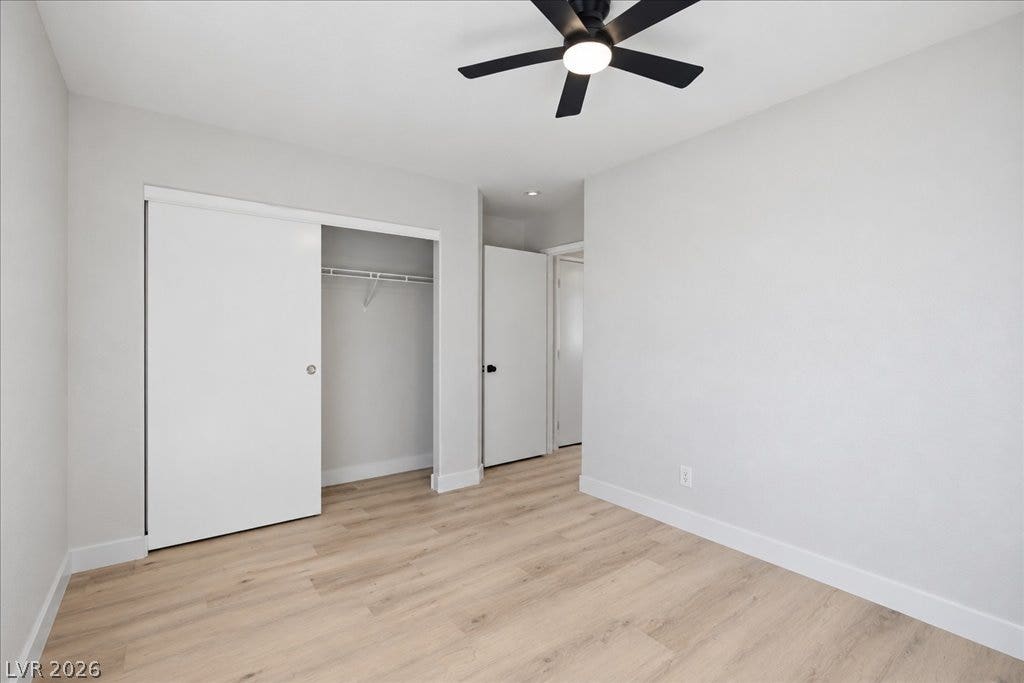 Smooth wood-style flooring and a built-in closet anchor this clean, modern bedroom space.