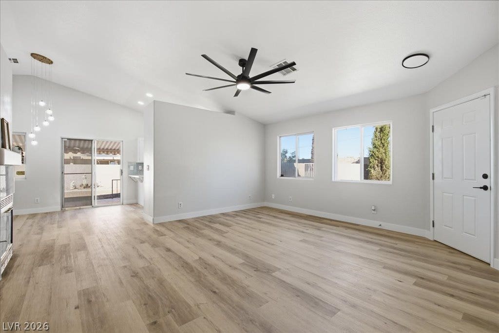 Vaulted ceilings and wood-style flooring enhance this open, sun-filled living space.