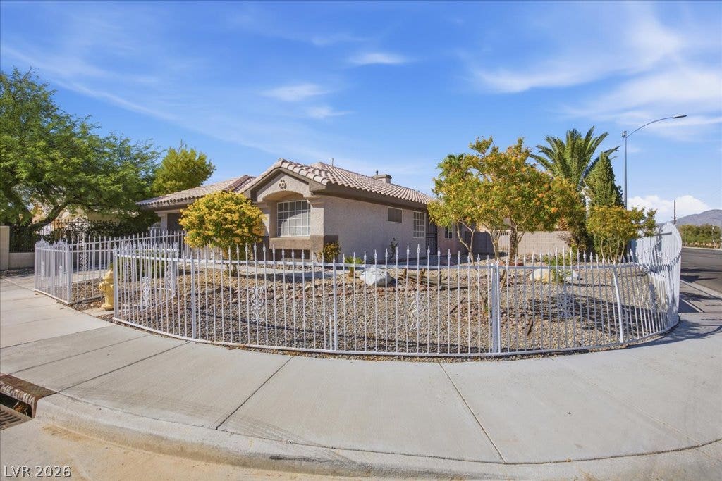 Manicured desert landscaping surrounds this single-story home on a prominent corner lot.