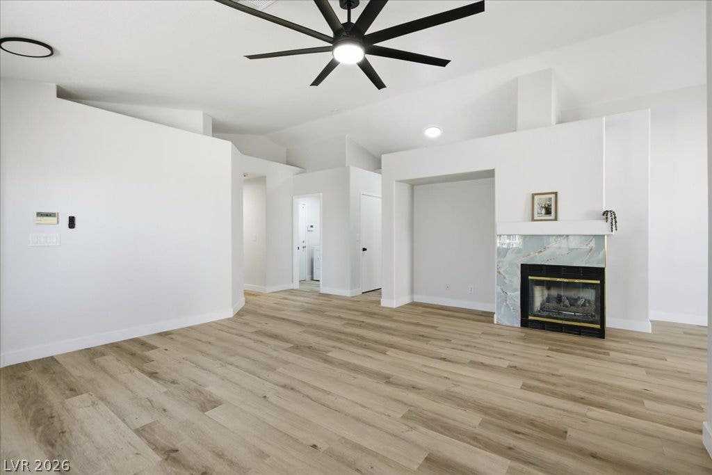 Warm wood-style flooring and a tiled fireplace anchor the open, high-ceilinged living space.