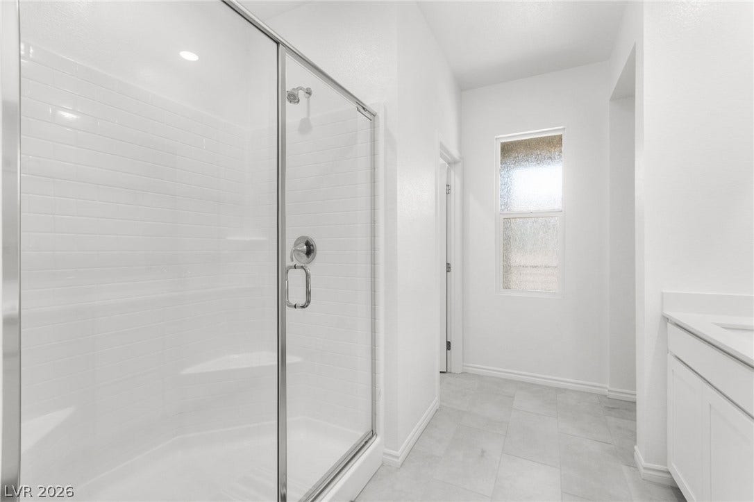 A spacious, naturally illuminated bathroom featuring a pristine glass-enclosed shower and modern fixtures.