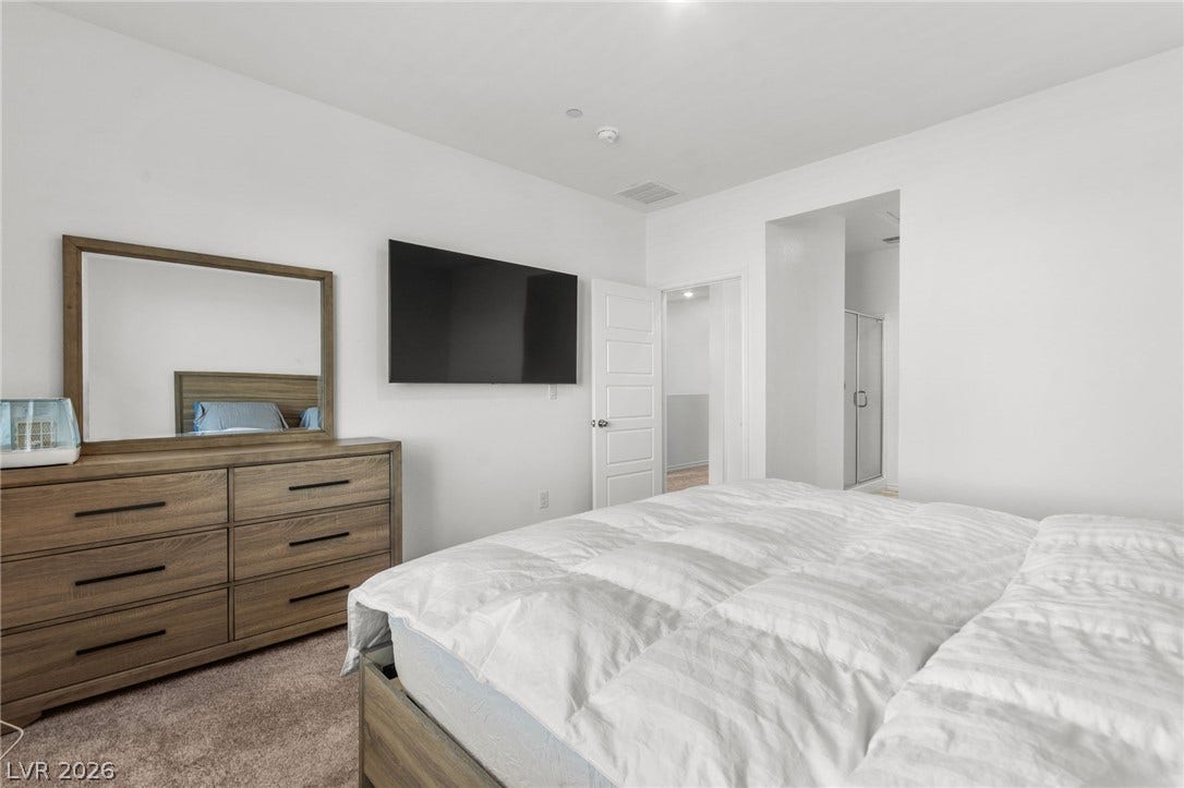 A well-appointed bedroom featuring light-toned flooring and a convenient doorway leading to an adjoining bath.