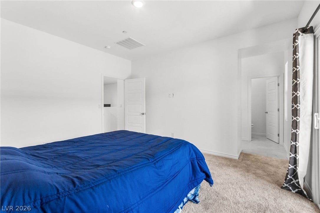 A restful retreat awaits in this bedroom, featuring plush carpeting underfoot.