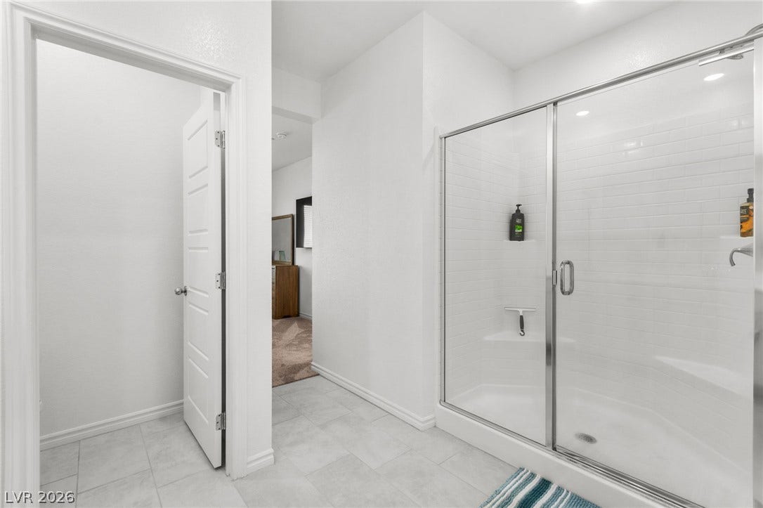 A streamlined walk-in shower with sleek glass doors offers modern comfort and easy maintenance.