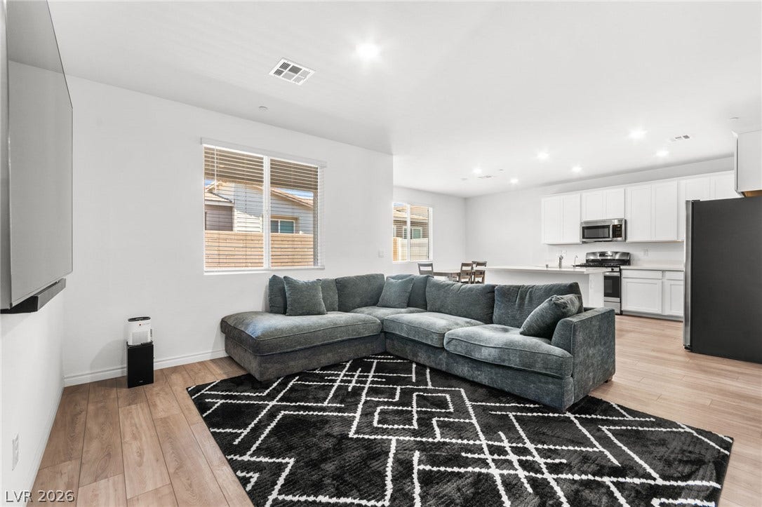 An open concept living area showcases beautiful flooring and an adjoining modern kitchen.