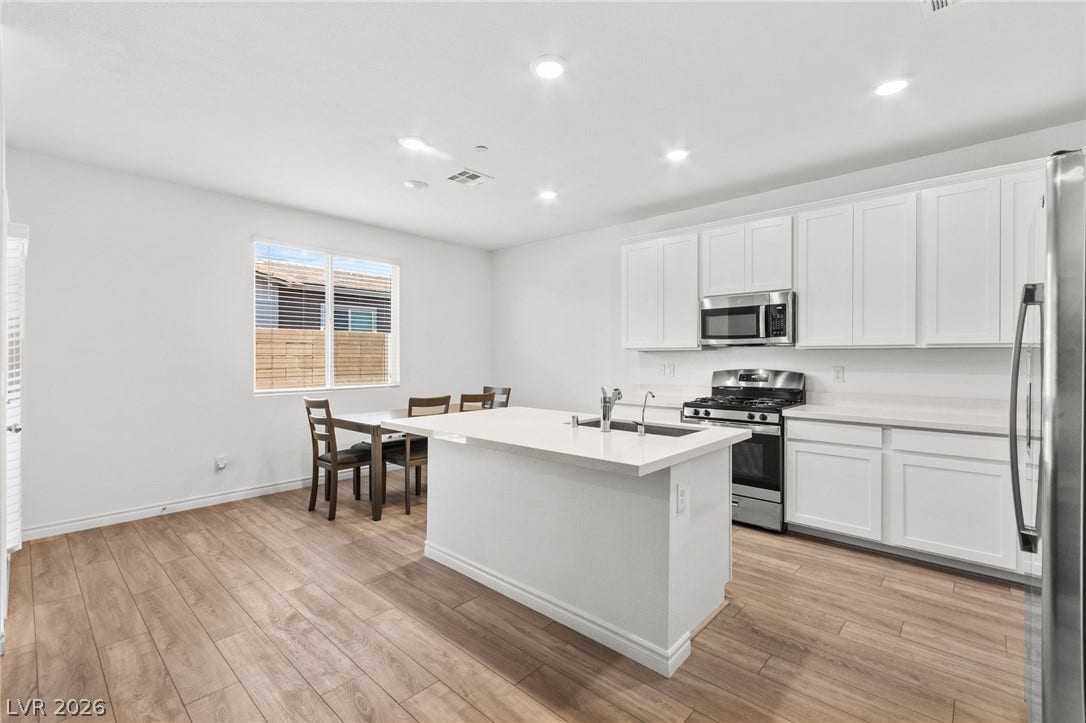 A pristine culinary space features an inviting kitchen island and a designated dining area, ideal for gathering.
