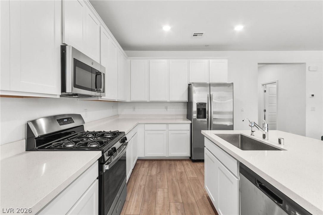 A well-equipped kitchen features white cabinetry and stainless steel appliances, offering a fresh, contemporary aesthetic.