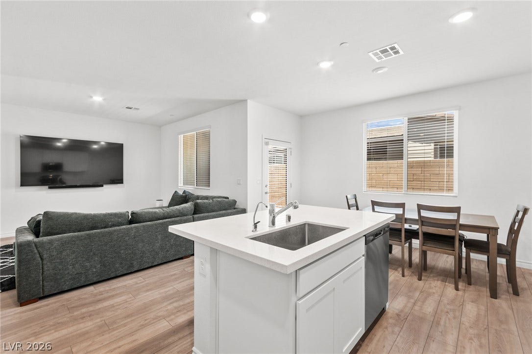 An open-concept living area boasts a sleek kitchen island and warm wood flooring throughout.