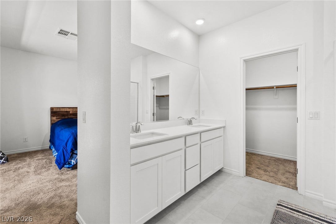 A well-lit primary bathroom features a double vanity with ample counter space and cabinet storage.