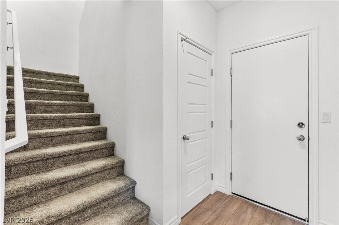 A well-designed entryway features practical wood flooring and carpeted stairs leading to upper levels.