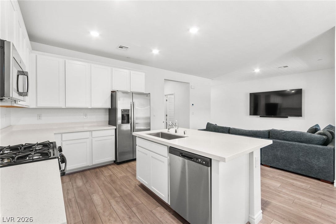 A well-lit kitchen with sleek countertops flows into a comfortable living area, offering a prime gathering space.
