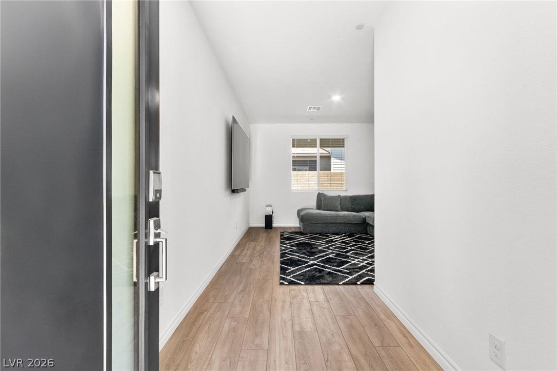A streamlined entry foyer, featuring light wood flooring leading into a living area.