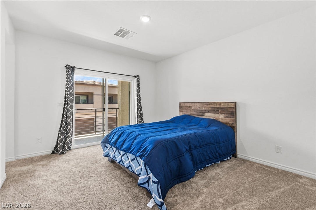 A comfortable retreat features plush carpeting and convenient sliding door access to a private balcony.