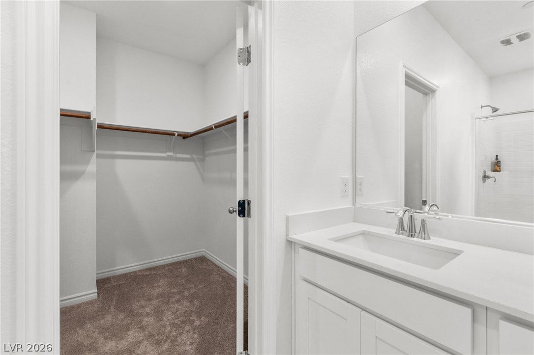 A well-lit primary bathroom with a spacious walk-in closet, providing ample storage and a refreshing atmosphere.