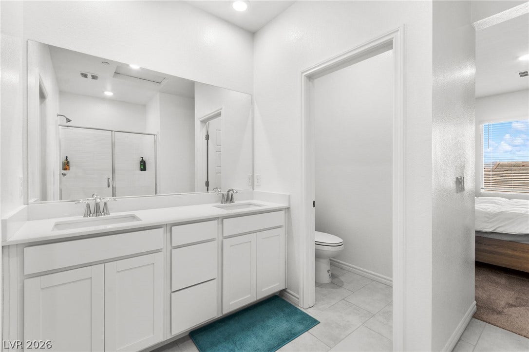 A pristine bathroom features a double vanity and a sleek glass-enclosed shower, offering ample space and contemporary design.