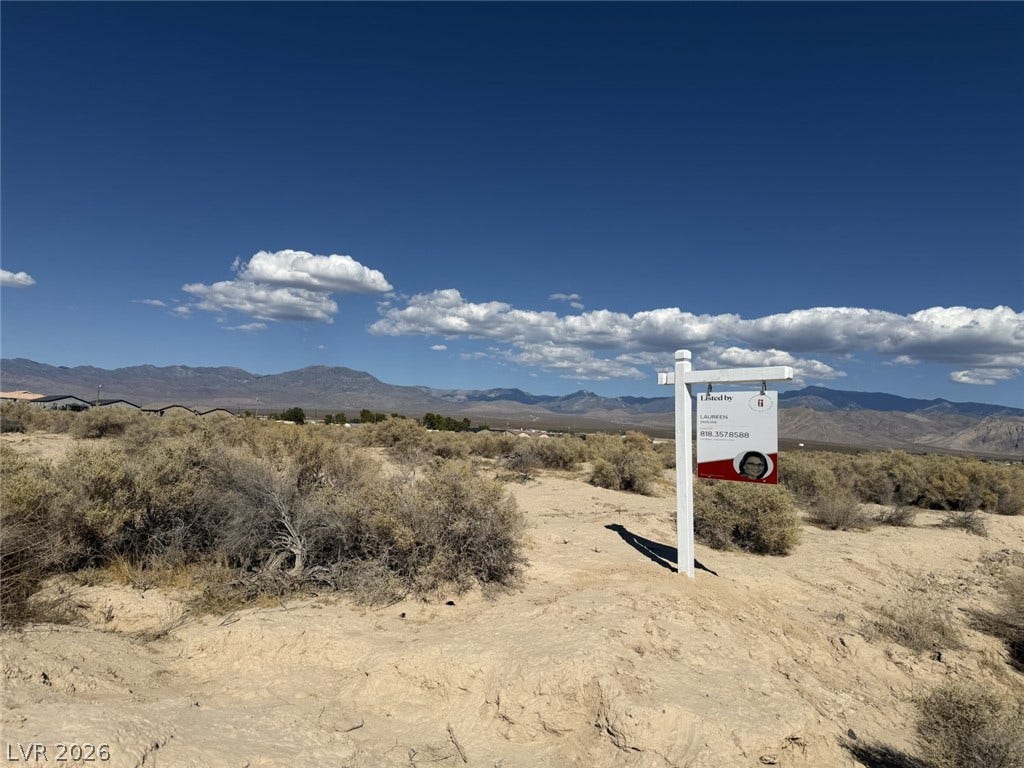1870 Elko Street, Pahrump, NV 89048 Panoramic mountain ridges frame this expansive desert lot under a clear blue sky.