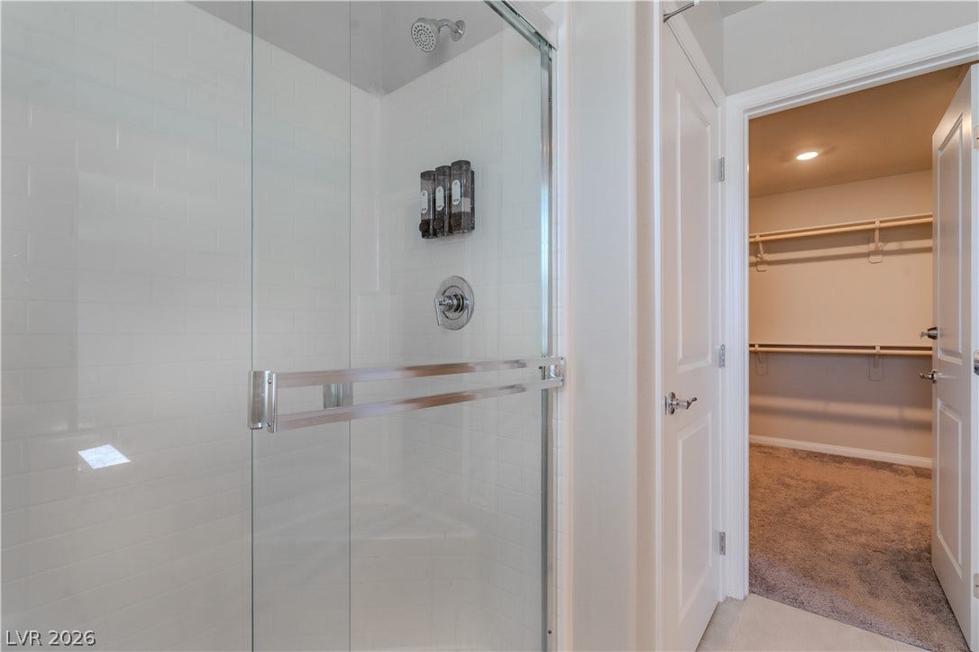 8920 Seal Cove Street, Las Vegas, NV 89178 A glass-enclosed shower stands adjacent to a spacious walk-in closet featuring plush carpeting.