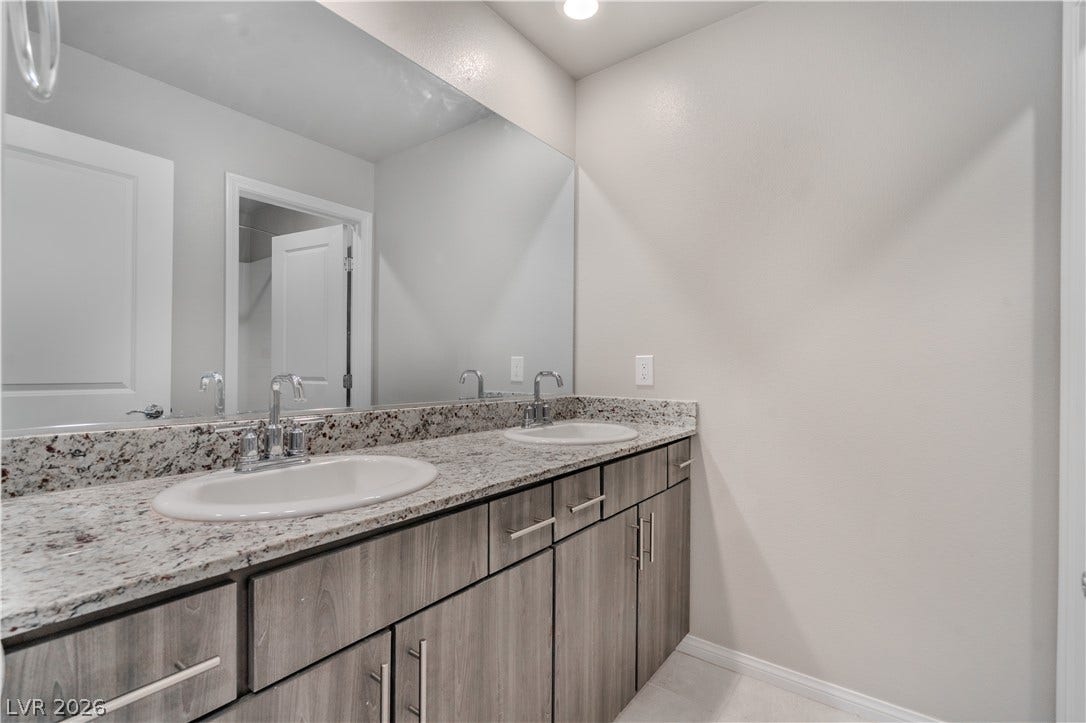 8920 Seal Cove Street, Las Vegas, NV 89178 Double vanity featuring granite counters and modern cabinetry highlights this updated bathroom space.