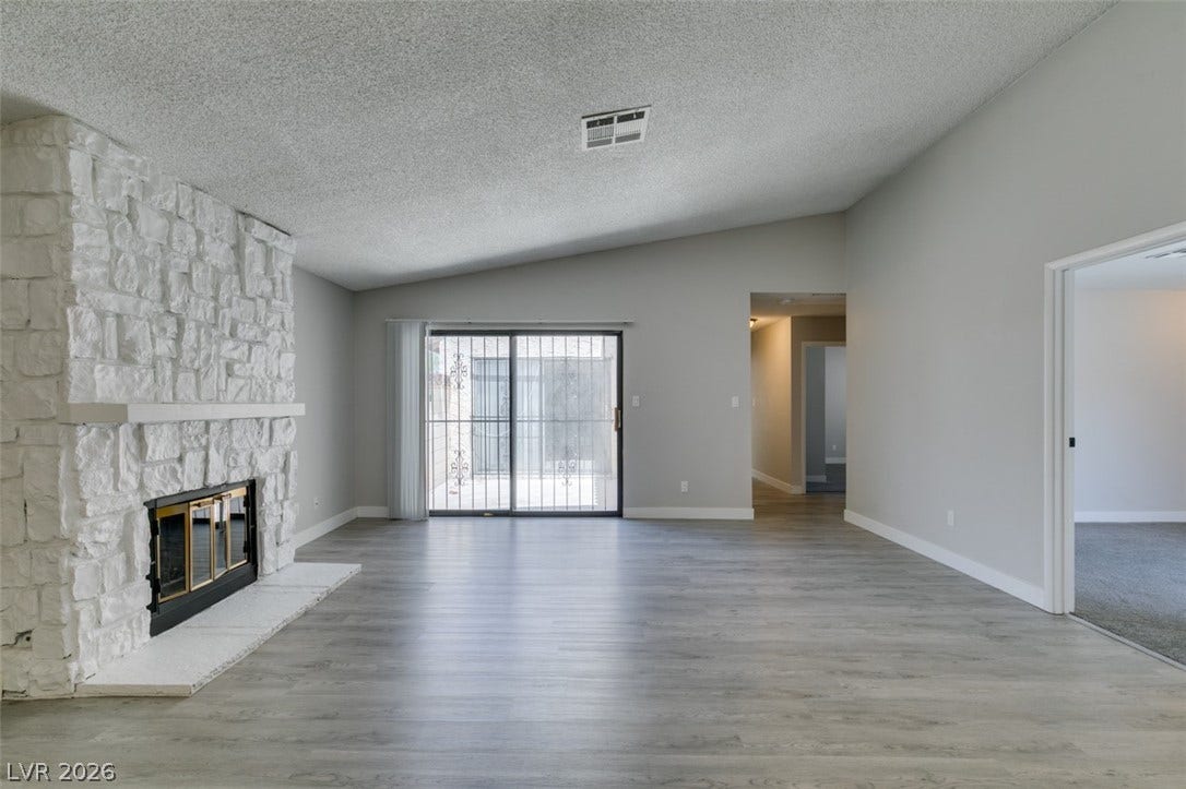 A spacious living area offers a striking stone fireplace and a glass sliding door for abundant natural light.