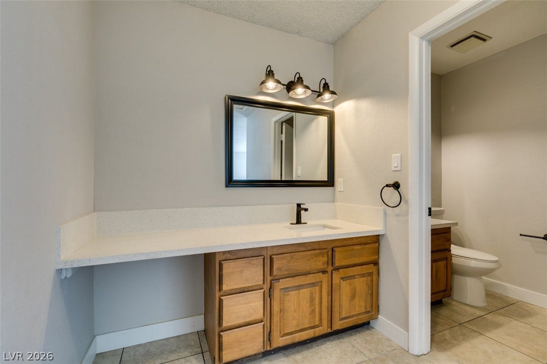 A well-lit bathroom features a generous vanity with integrated sink and functional cabinetry.