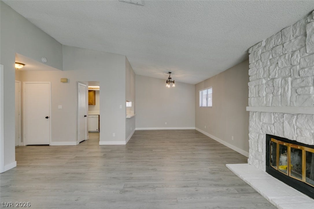 A spacious living area with a vaulted ceiling and a prominent stone fireplace, ideal for relaxation and entertaining.