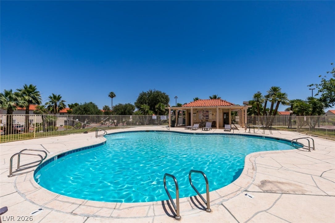 A refreshing outdoor pool beckons under a clear sky, featuring ample deck space and a charming poolside cabana.
