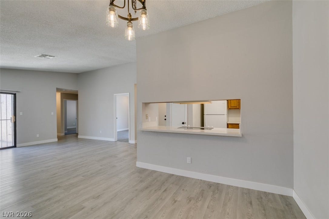 A well-lit living area features attractive flooring and a convenient pass-through window to the kitchen.