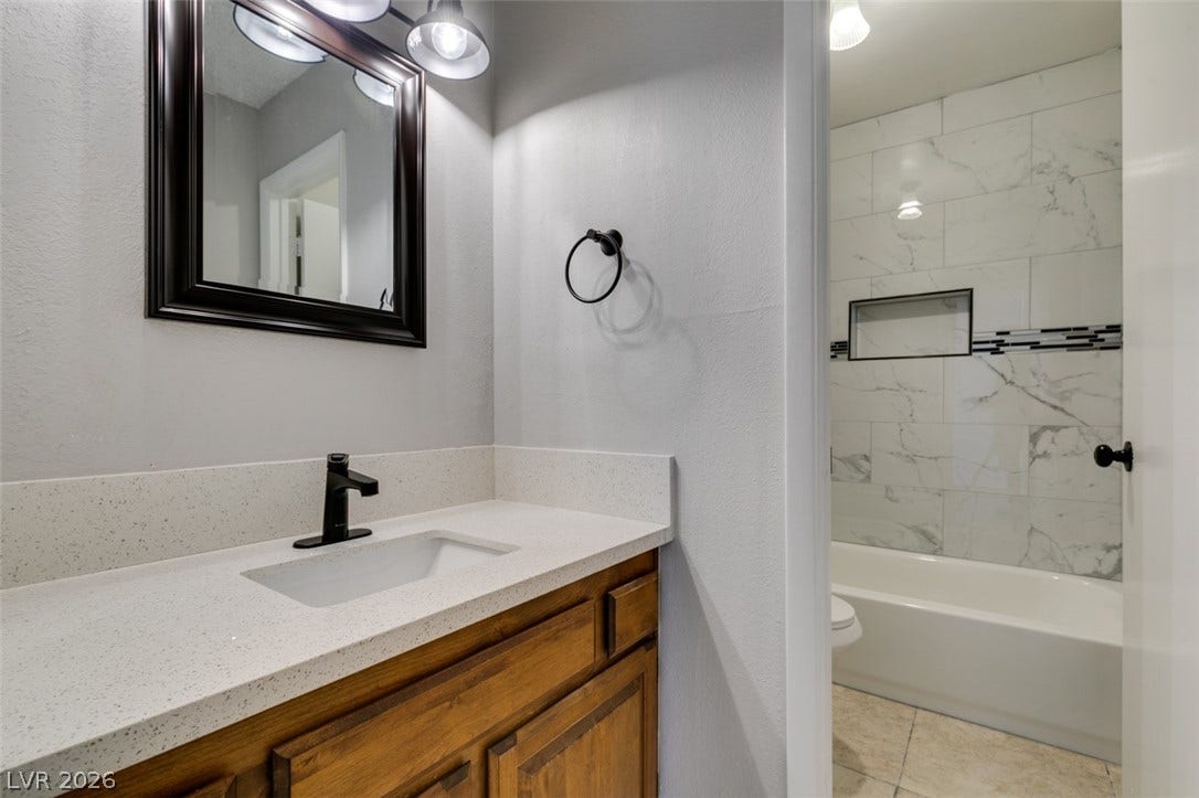 Modern bath with spacious vanity and elegant tiled tub/shower.