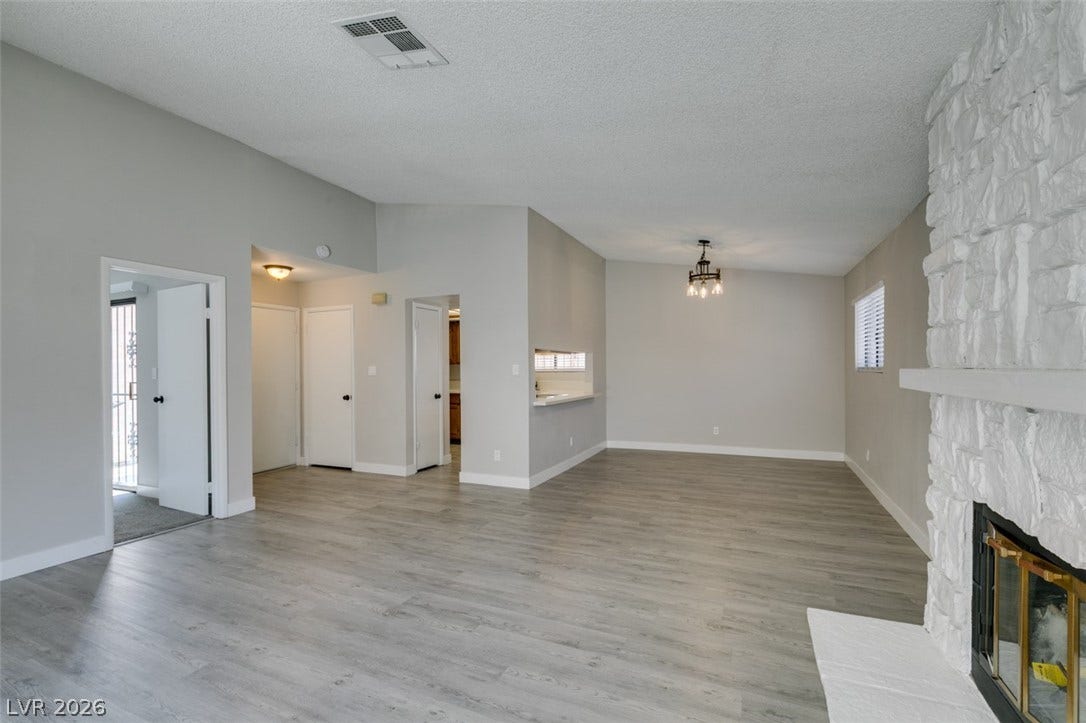 A whitewashed brick fireplace anchors this inviting living space with light wood-style flooring.