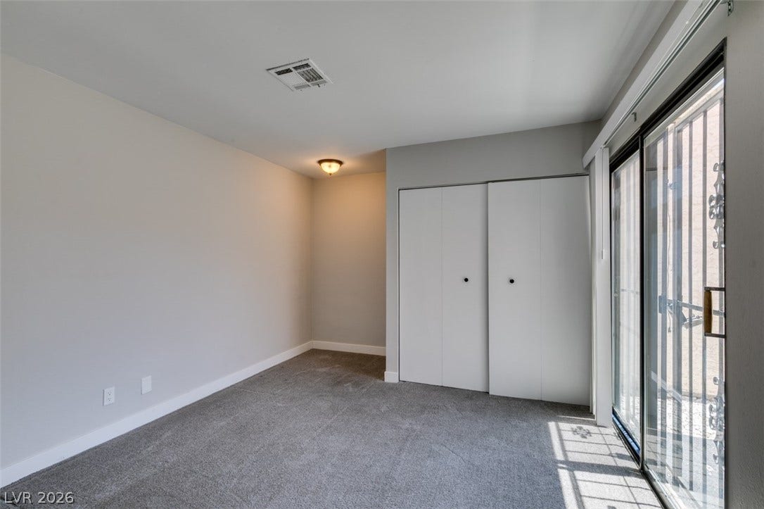 A well-lit room offering plush carpeting and sliding glass doors to outdoor access.