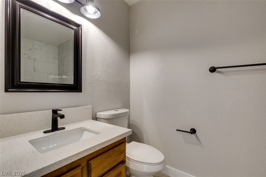 A well-appointed bathroom features a crisp white vanity and modern fixtures, reflecting a shower with subway tile.