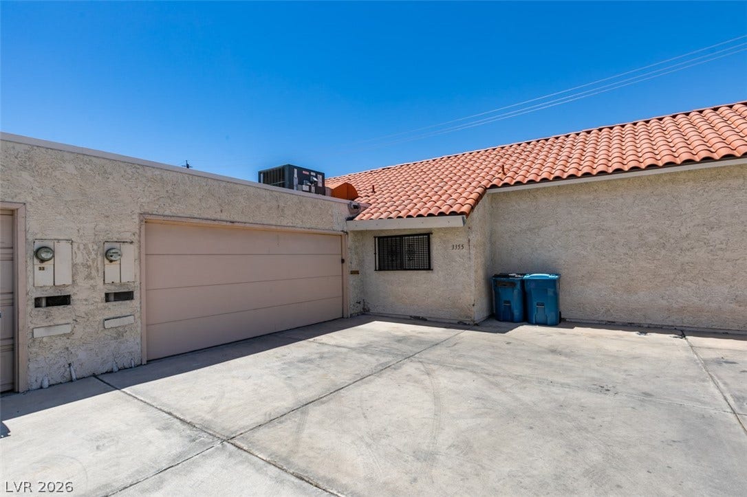 A terracotta-tiled roof crowns this residence, featuring a secure garage and ample paved parking.