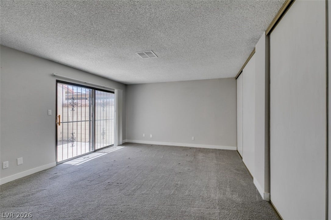 A spacious primary bedroom features soft carpeting, a large sliding glass door, and abundant closet space.