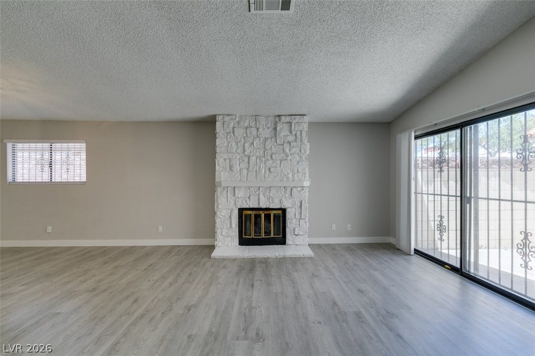 A striking stone fireplace and durable wood-look flooring distinguish this inviting living area.