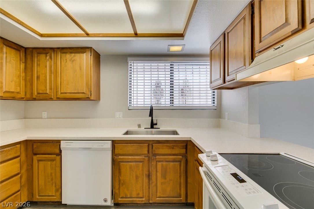 Prepare meals in a well-equipped kitchen featuring ample cabinetry and smooth countertops.