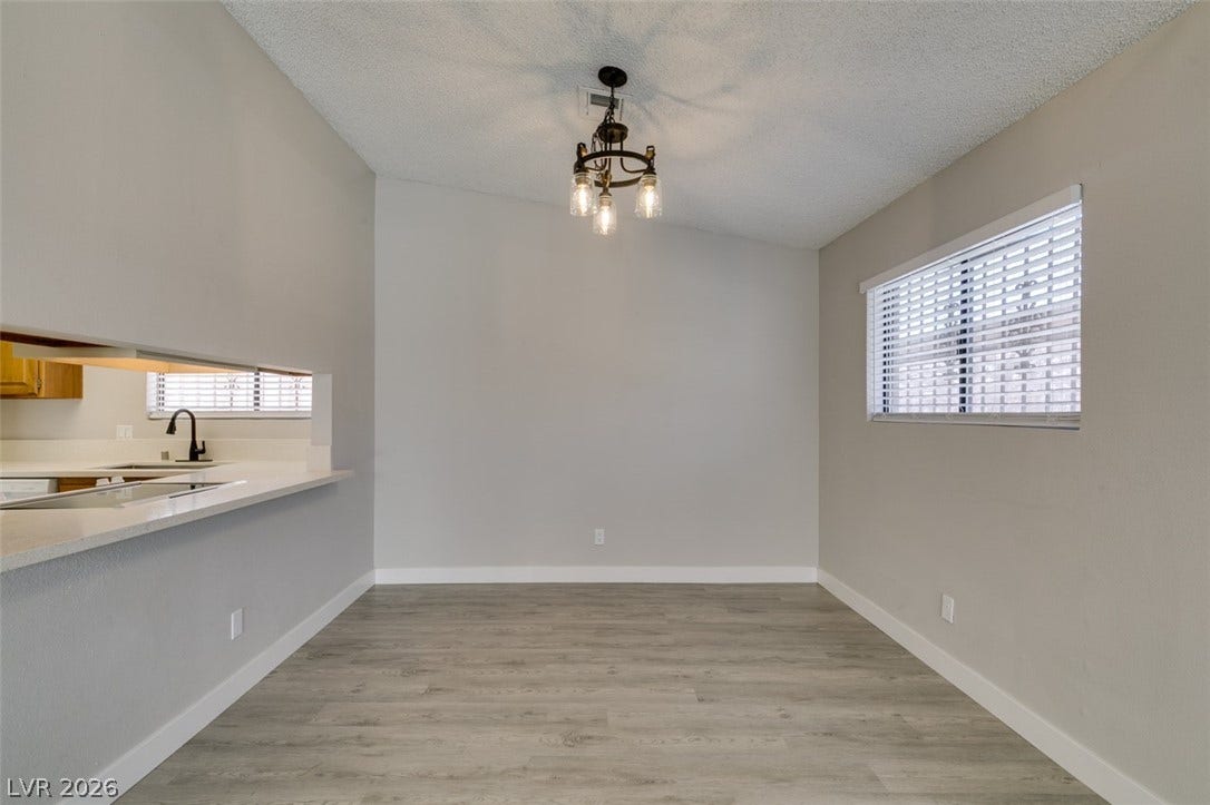 A refined dining space features a pass-through to the kitchen and an elegant chandelier.