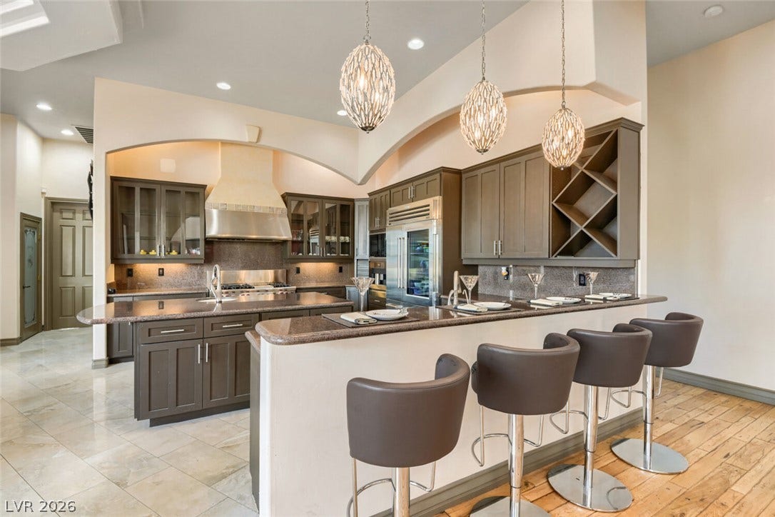 2010 Shenley Court, Las Vegas, NV 89117 An open kitchen displays two-tier stone counters alongside extensive custom cabinetry and recessed lighting.