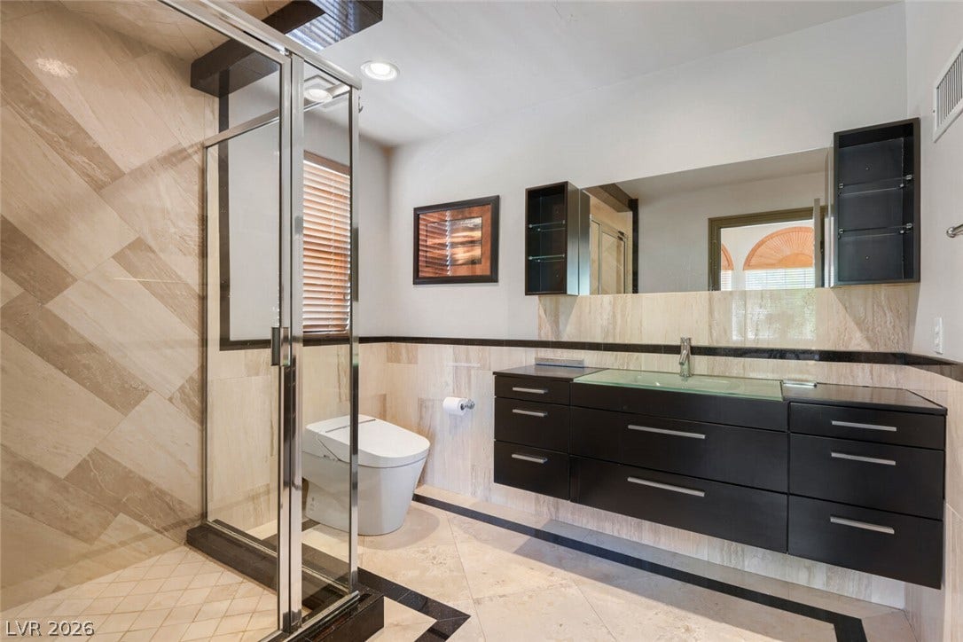 2010 Shenley Court, Las Vegas, NV 89117 Stone tile finishes and a floating vanity define this contemporary bathroom space.