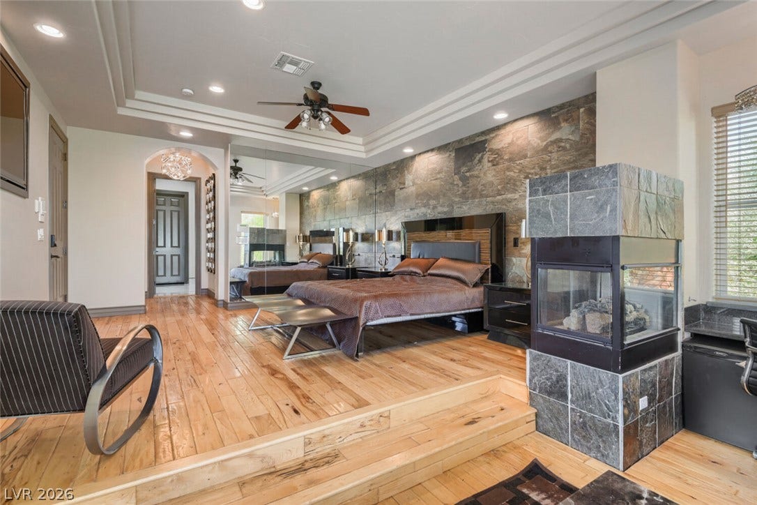 2010 Shenley Court, Las Vegas, NV 89117 Polished hardwood floors and a modern stone fireplace frame this elevated primary bedroom retreat.