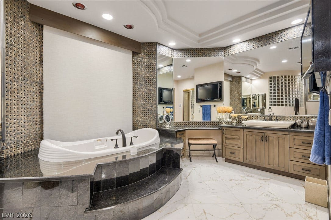 2010 Shenley Court, Las Vegas, NV 89117 An elegant soaking tub highlights this bathroom featuring natural stone tile flooring and intricate wall accents.