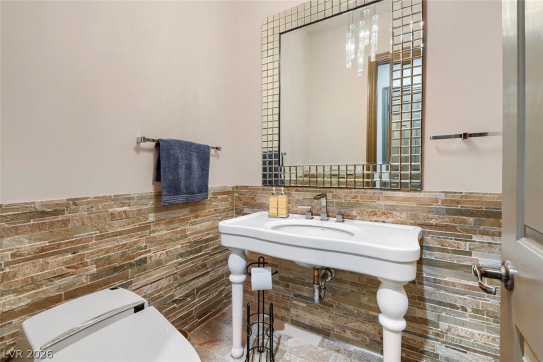 2010 Shenley Court, Las Vegas, NV 89117 Natural stone wainscoting and a classic console sink bring distinct character to this powder room.