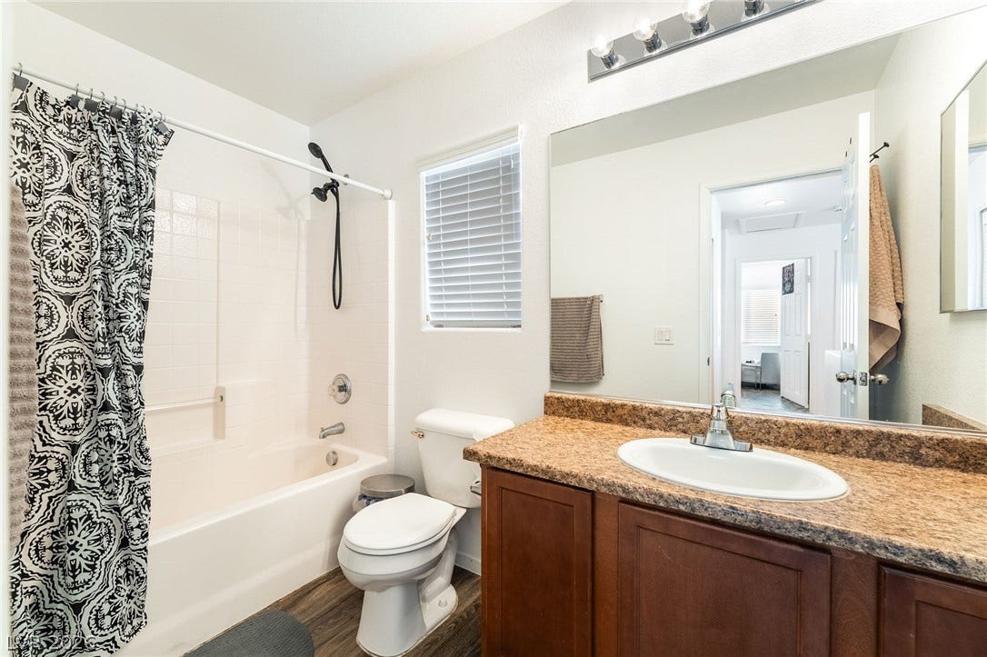 6275 Felicitas Avenue, Las Vegas, NV 89122 Stone-look countertops and deep wood cabinetry anchor this classic full bathroom.
