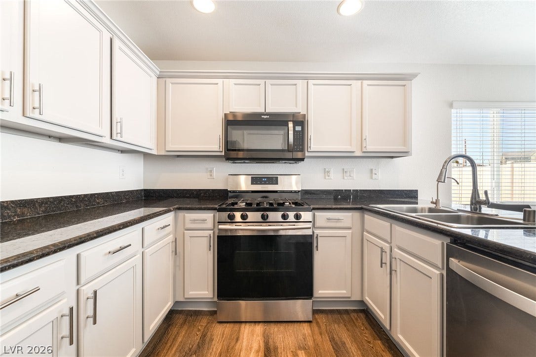 6275 Felicitas Avenue, Las Vegas, NV 89122 Rich wood flooring pairs with clean cabinetry and dark stone counters in this modern workspace.