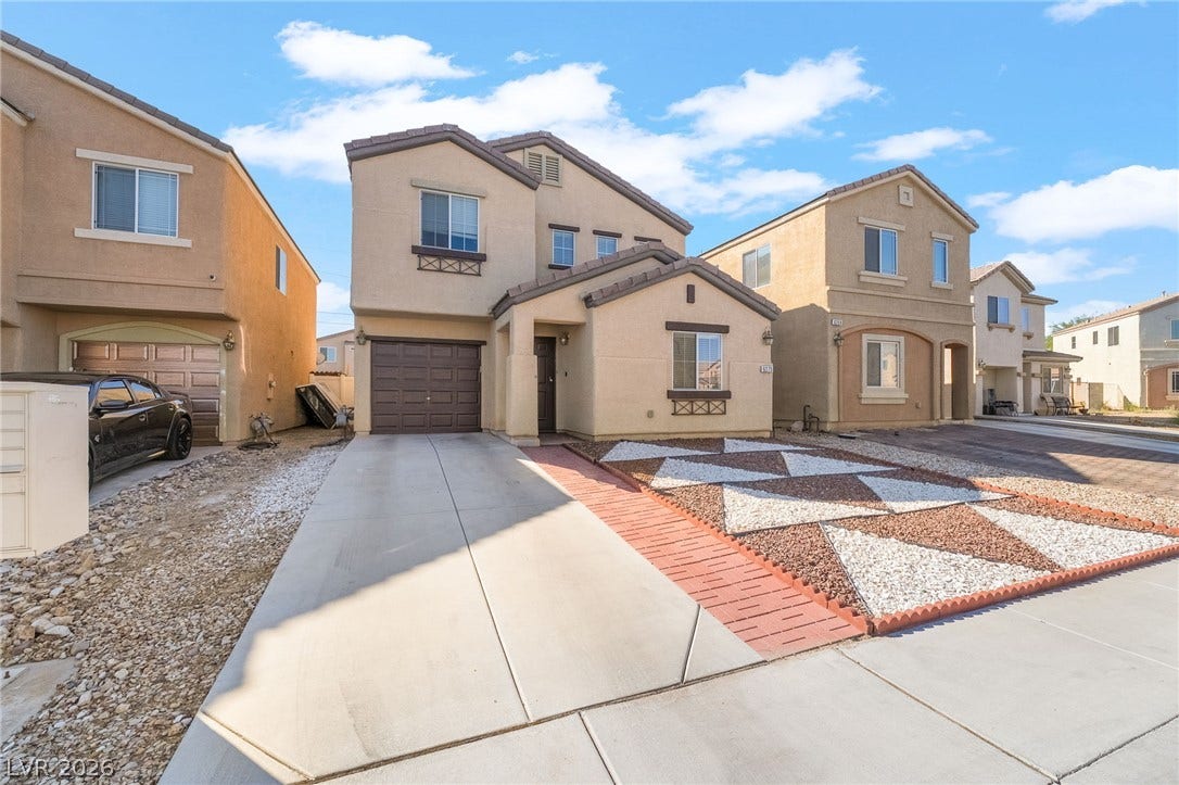 6275 Felicitas Avenue, Las Vegas, NV 89122 A classic stucco exterior sits behind a paved concrete driveway and geometric desert landscaping.