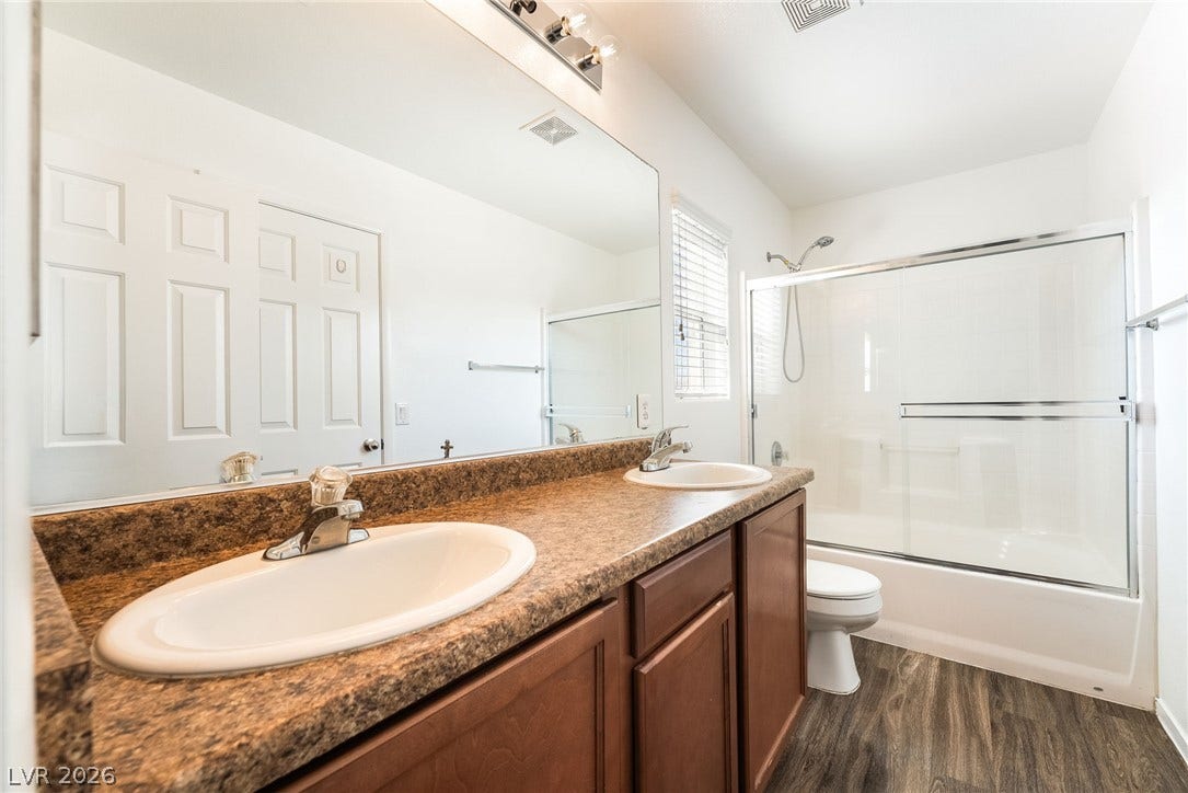 6275 Felicitas Avenue, Las Vegas, NV 89122 Double vanities and a glass-enclosed tub shower highlight this functional bathroom space.