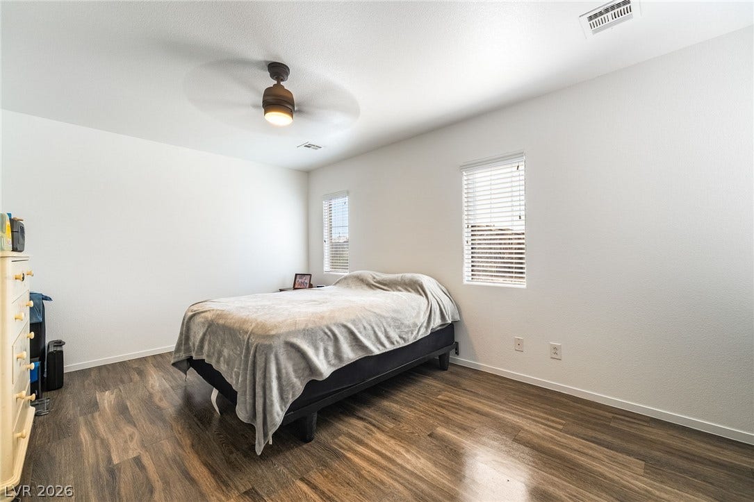 6275 Felicitas Avenue, Las Vegas, NV 89122 Rich wood-inspired flooring and clean white walls anchor this airy bedroom space.