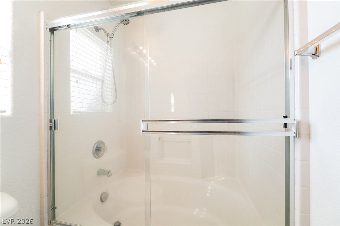 6275 Felicitas Avenue, Las Vegas, NV 89122 Sliding glass doors enclose a soaking tub and shower combo under a bright window.